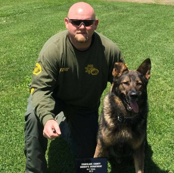 A man kneeling next to a dog with a plaque for the Events - Chris Oliver Seminar.